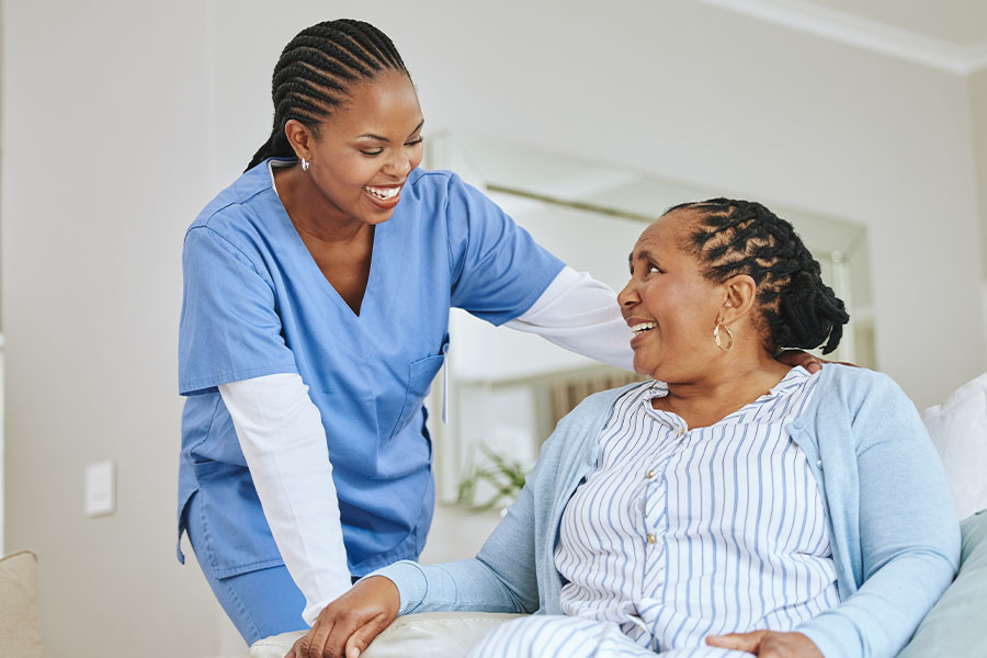 Assistant helping patient in hospital bed.