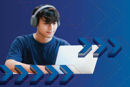 A student wears headphones and works on a laptop