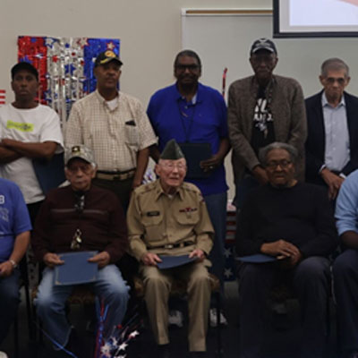 Veterans pose for a photo with some sitting and some standing behind them