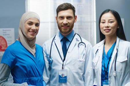 three people in lab coats and wearing stethoscopes