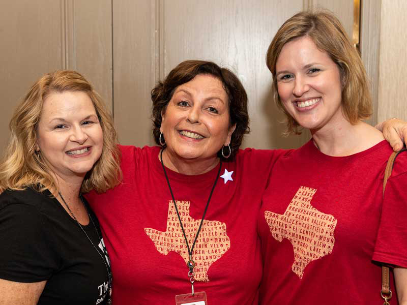 3 female staff of Dallas College hugging and smiling