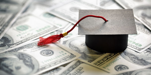 graduation hat sitting on top of a lot of one-hundred dollar bills