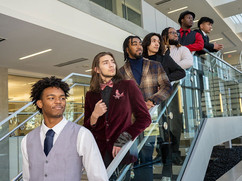 A group of formally dressed male students standing on a staircase.