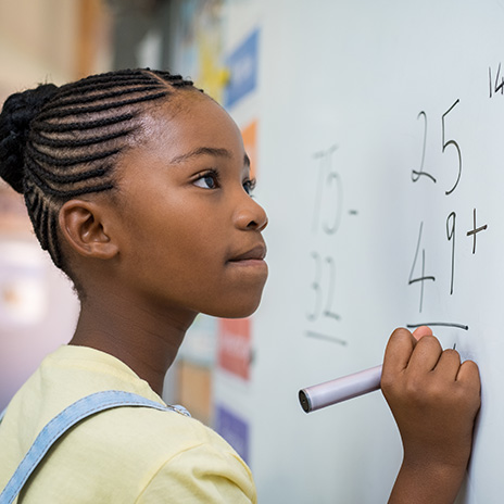 A student completes math problems on a white board