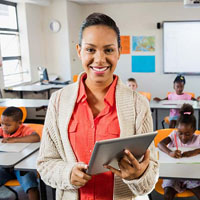 A teacher holds a notepad in the middle of her classroom