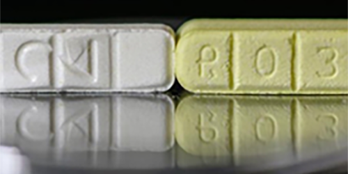Two pills - white pill on the left is pure Xanax and the yellow pill on the right is synthetic Xanax.