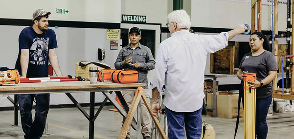 Four people stand around a workbench with tools in an industrial workshop