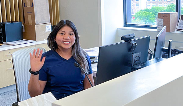 An employee waves behind the front desk at the dental center