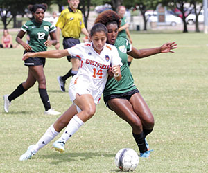 An Eastfield soccer runs alongside an opposing player while dribbling the ball down the field