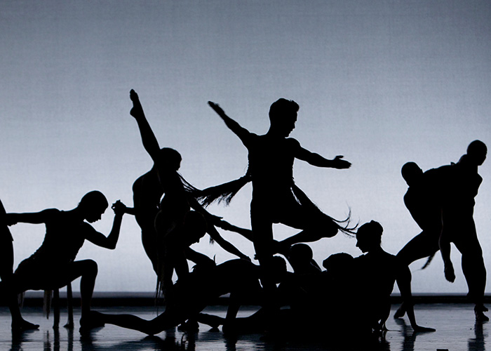 Students perform a dance number silhouetted against a light blue background
