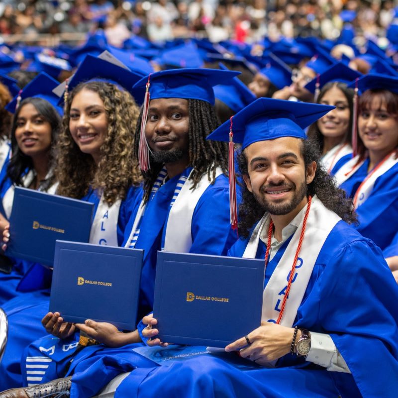 Students at graduation sit on the graduation arena floor