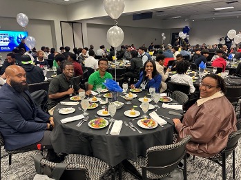 Students at the Male Achievement Summit sit at tables and enjoy dinner
