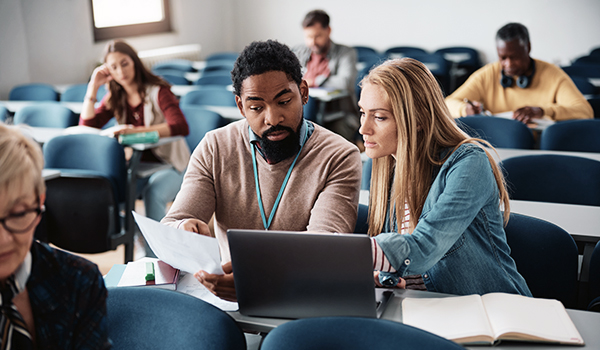 Students review a paper in their classroom together